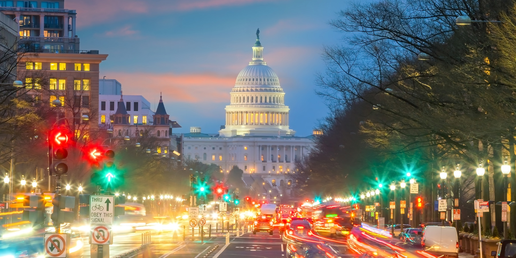 Capitol Building at night with road in front, blurred car and traffic lights on road