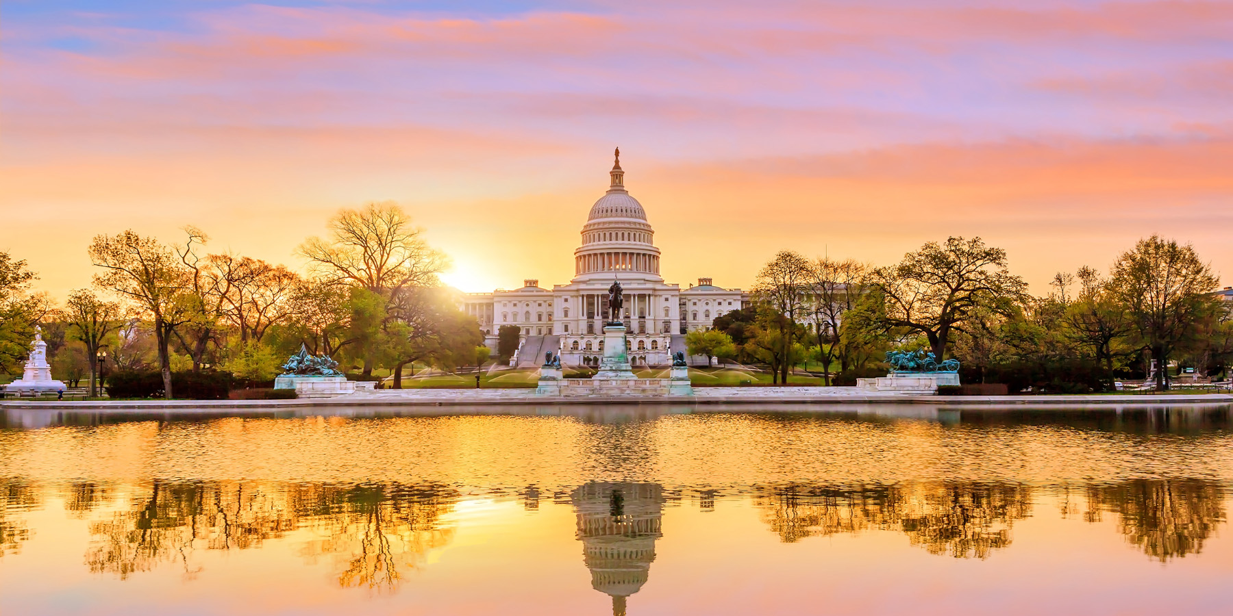 Capitol building at sunrise, with capitol building reflected in water in front of building